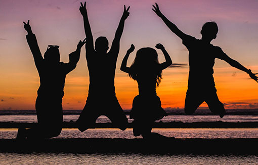 A silhouette of a group of students celebrating on the beach