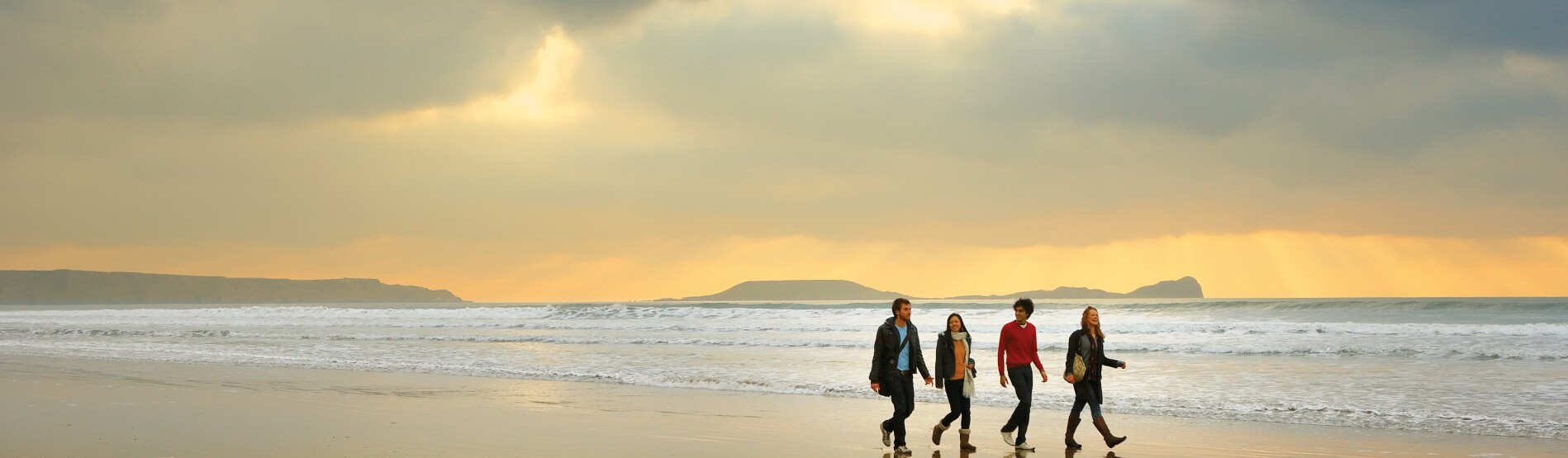 students walking on beach with sunset 