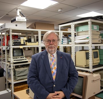 John Tucker in front of shelving units