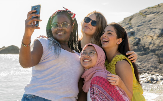 Four students taking a photo on the beach