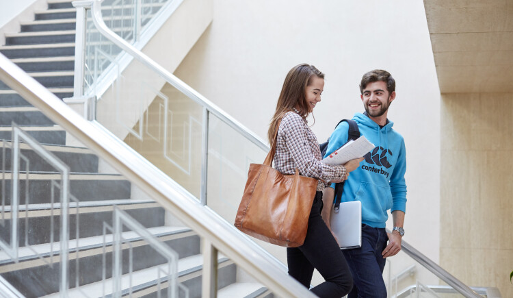 Two students talking in seated area.