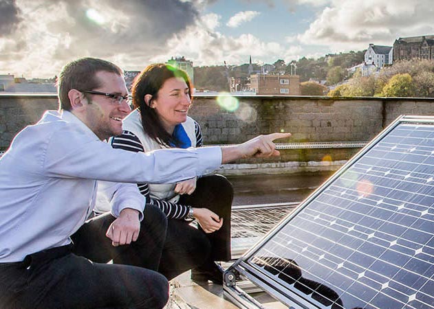 Ffot o ddau o bobl yn pwyntio mewn panel solar