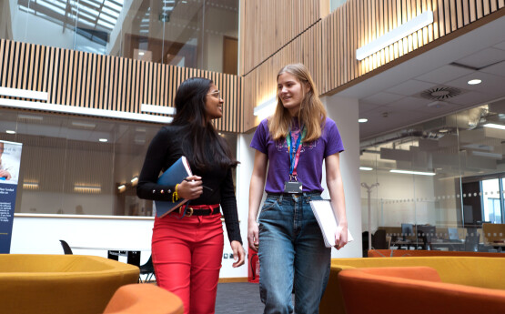 Two girls walking through a library