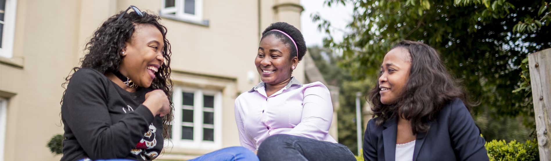 Two students laughing while chatting on the steps of the singleton abbey