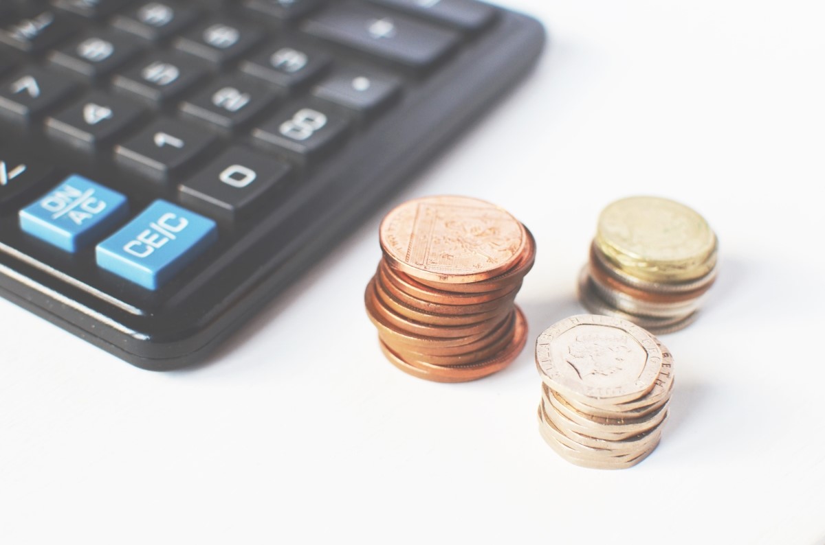 Calculator with piles of British coins next to it