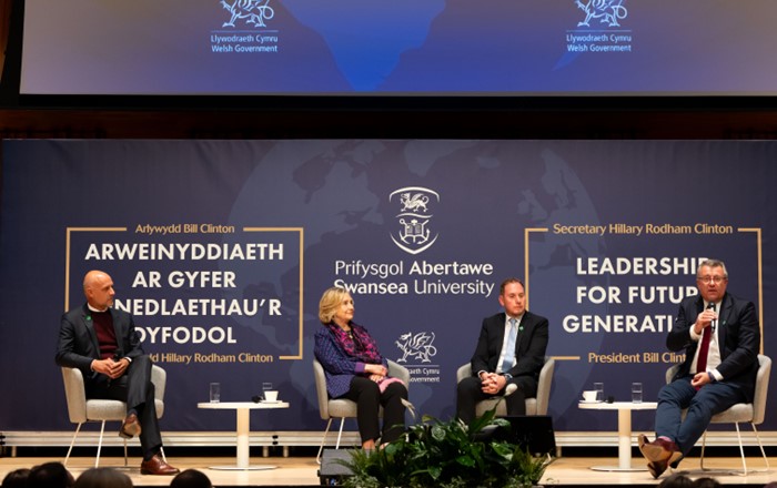 Llun o Nick Gliddon, Cyfarwyddwr Busnes Vodafone, ar y llwyfan yn y digwyddiad gyda'r Ysgrifennydd Hillary Clinton, y Cynghorydd Rob Stewart, Cadeirydd Cyd-bwyllgor Dinas-ranbarth Bae Abertawe, ac Andrea Dona, Cyfarwyddwr Rhwydwaith a Datblygu Vodafone.