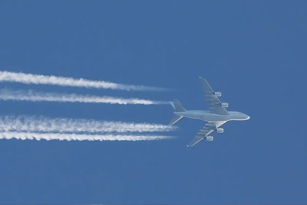 Awyren yn hedfan gyda contrails y tu ôl iddo