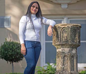 Student smiling at the camera standing against a statue.