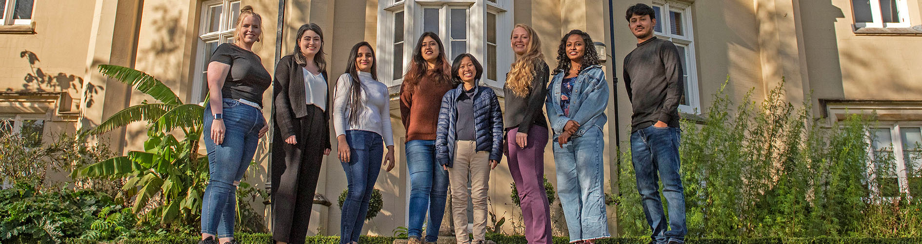 Students standing on stair, smiling at the camera.