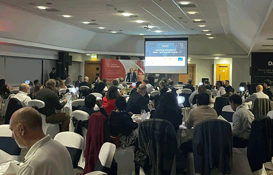 person standing and speaking to a busy room of evening guests