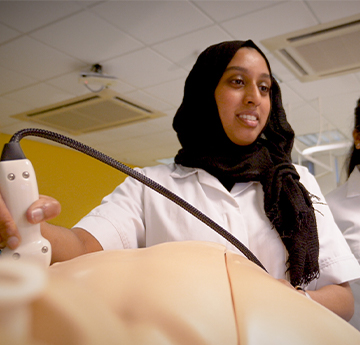 Student practising heart exam on a doll. 