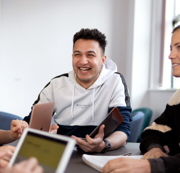 student sitting at a table talking with other students