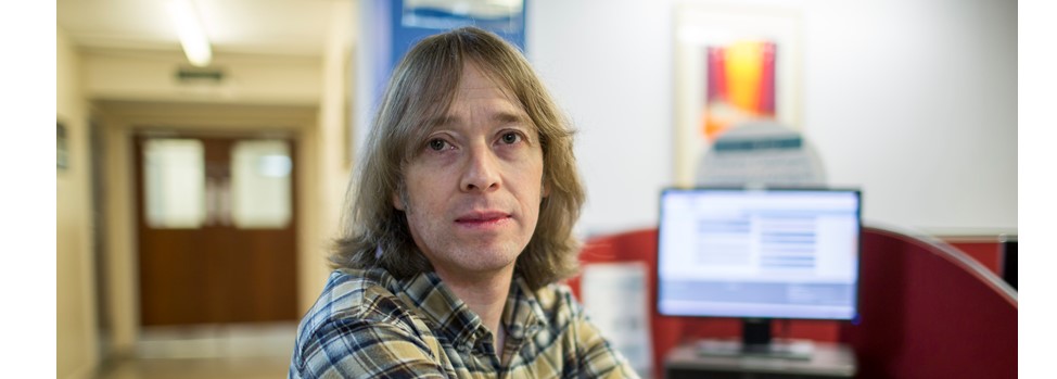 Professor Phil Reed with computer screen in background.