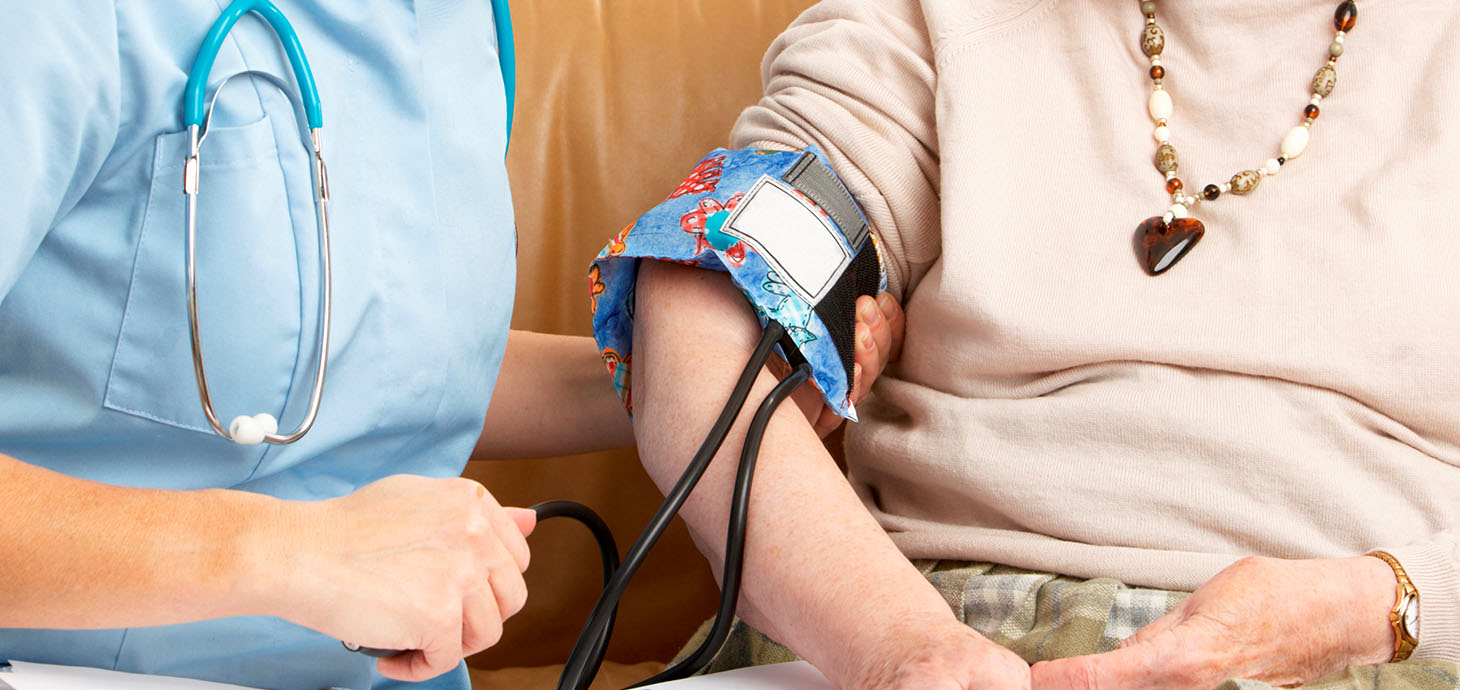 An elderly woman having her blood pressure taken by a nurse in her home 