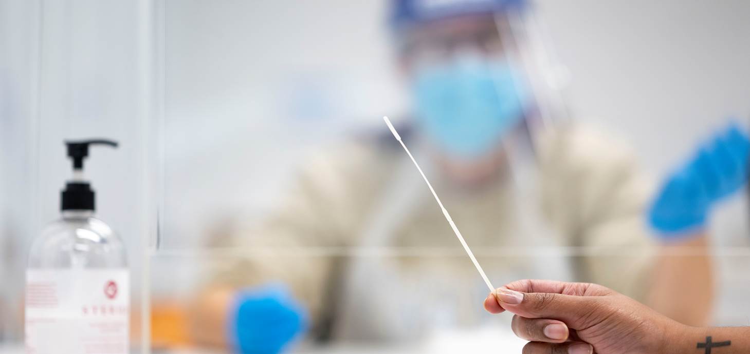 A woman's hand holding a Covid-19 test swab