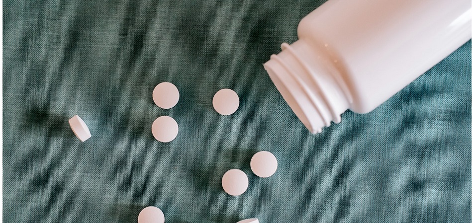 Image shows pill bottle and pills.