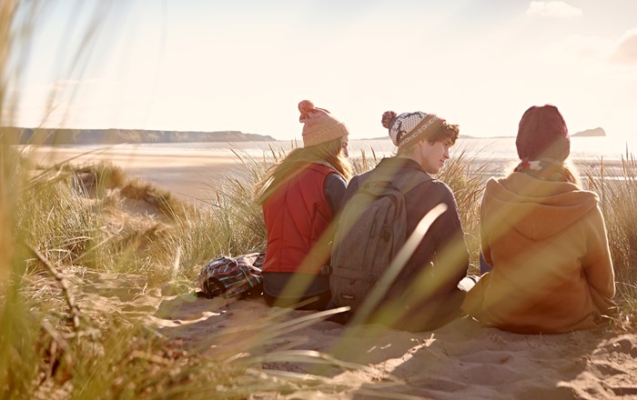 Three students sat on a beach 