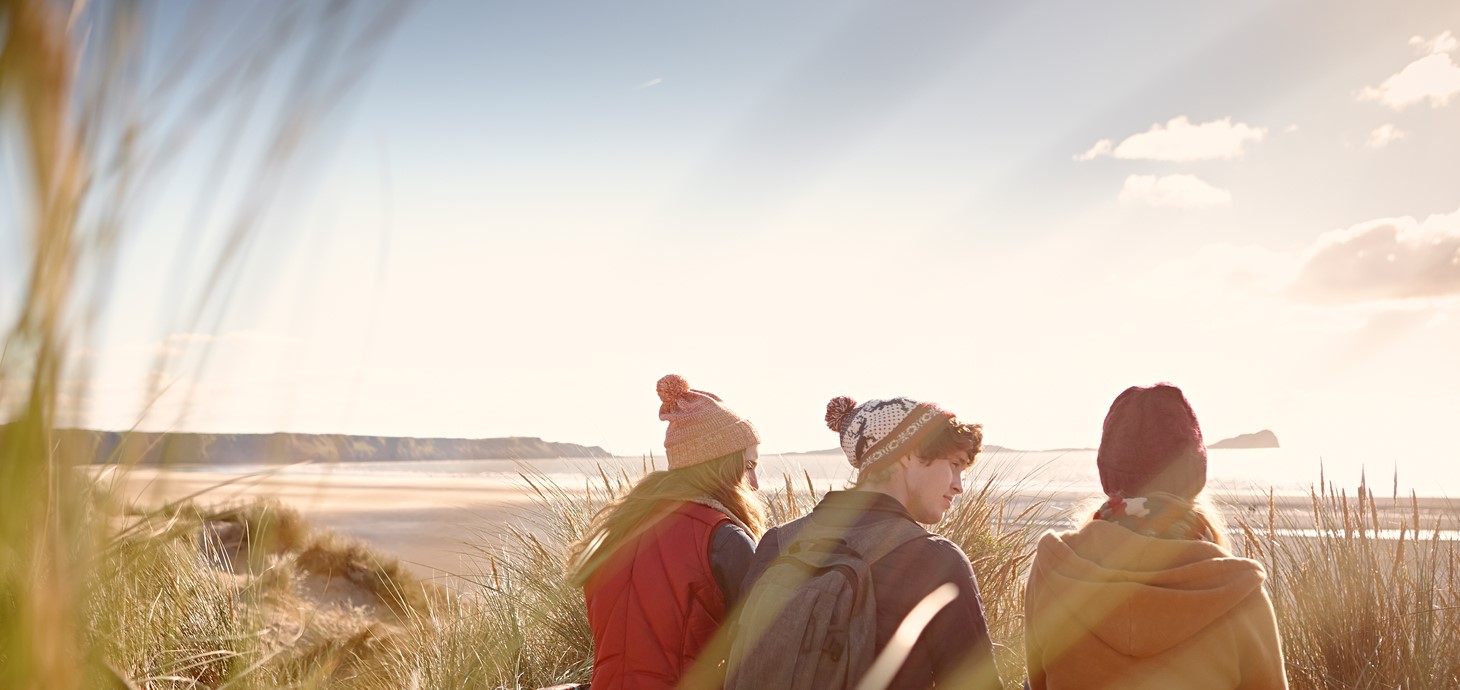 Three students sat on a beach 