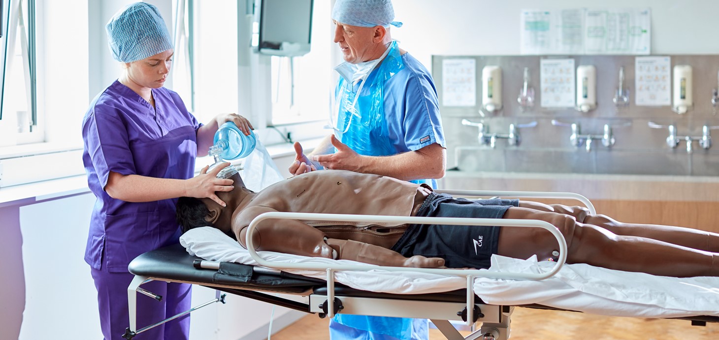 Two people wearing scrubs in a clinical room