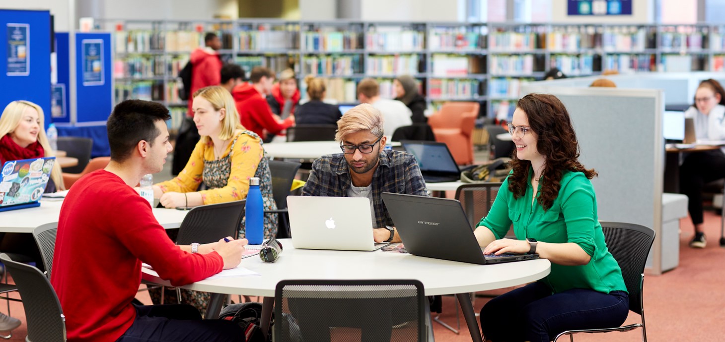 A group of students sat at a table using laptops