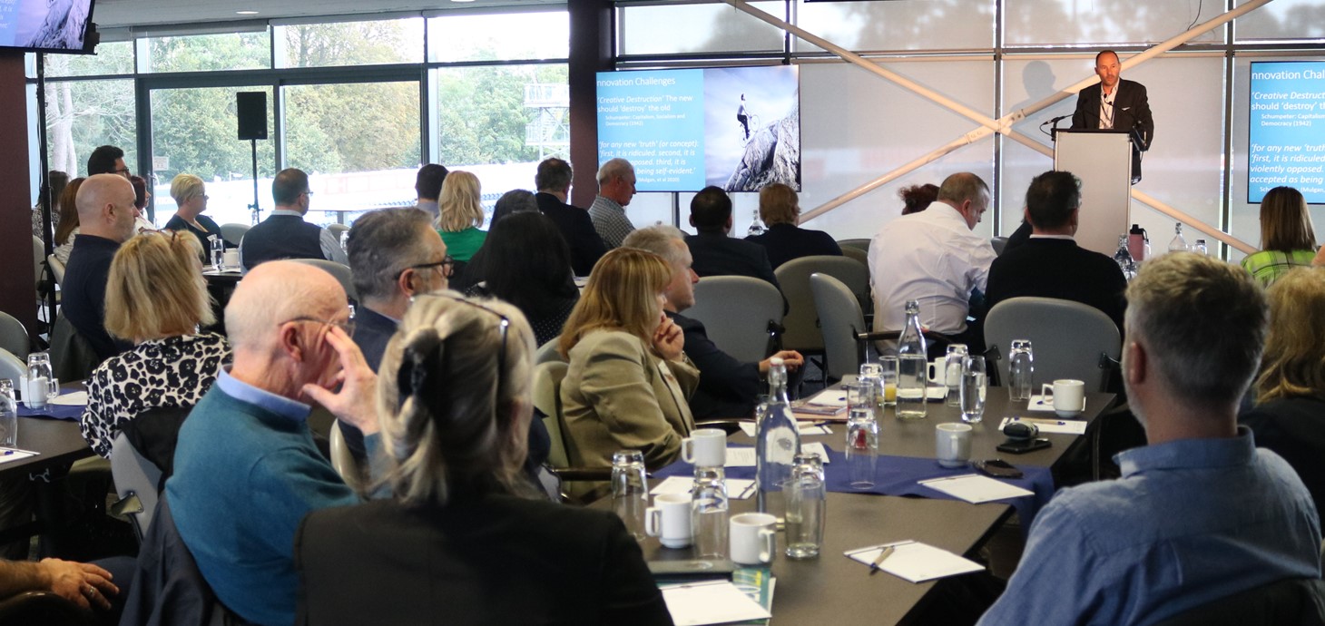 Man standing at a podium delivering a speech to a room of people