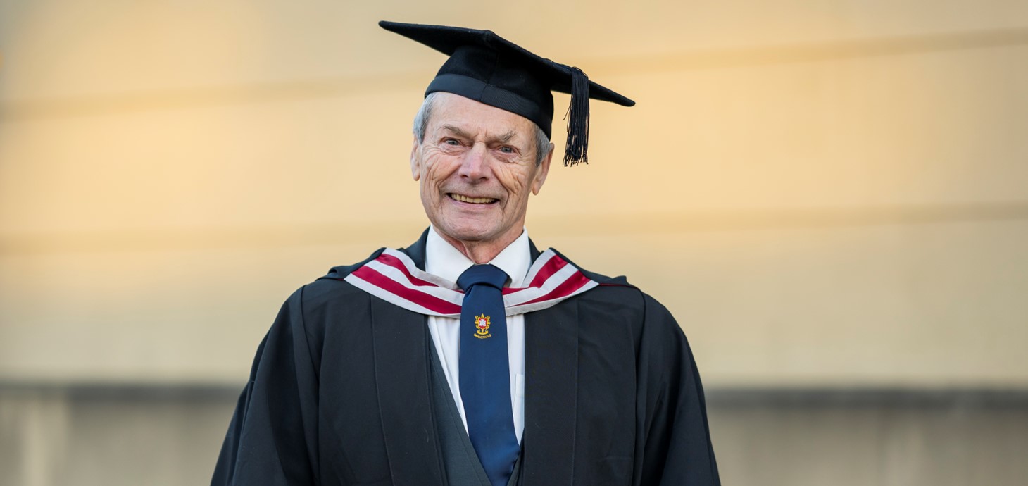 A photo of John in his cap and gown at graduation.