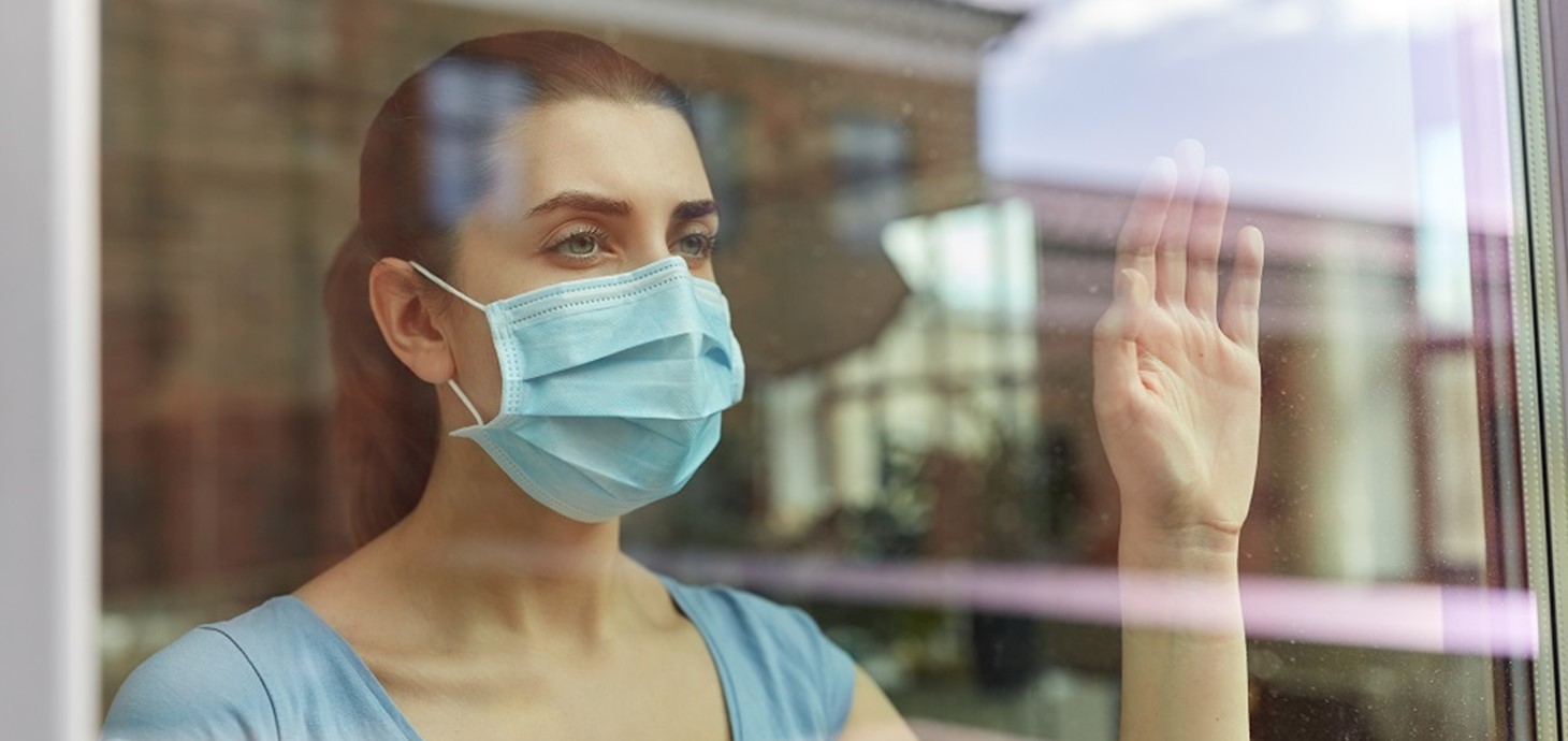 Woman at window wearing mask