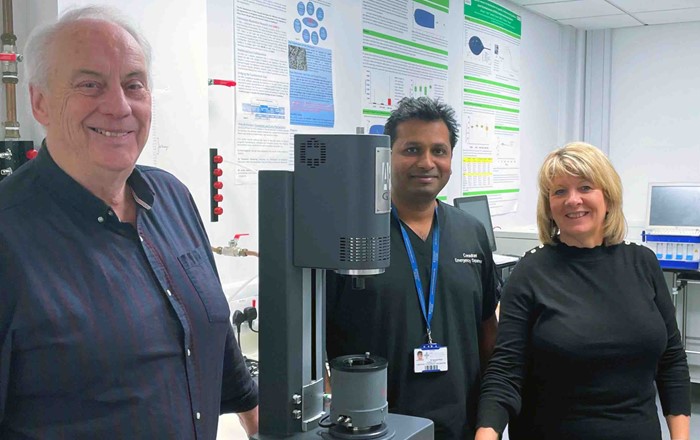 Two men and a woman standing in a medical research laboratory