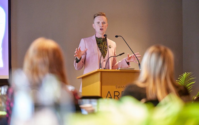 Man standing at a lecturn speaking to an audience