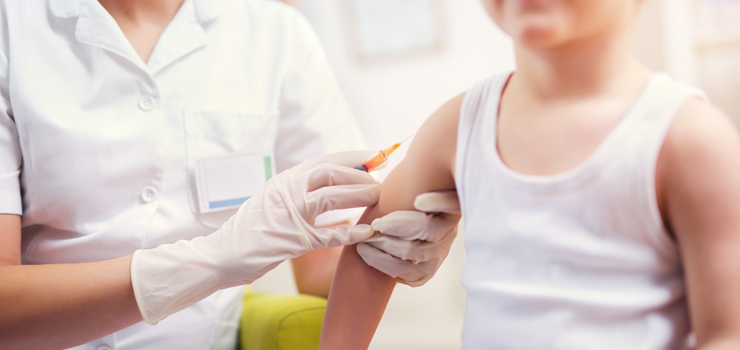 Child in vest being given vaccination in the army by a healthcare professional 