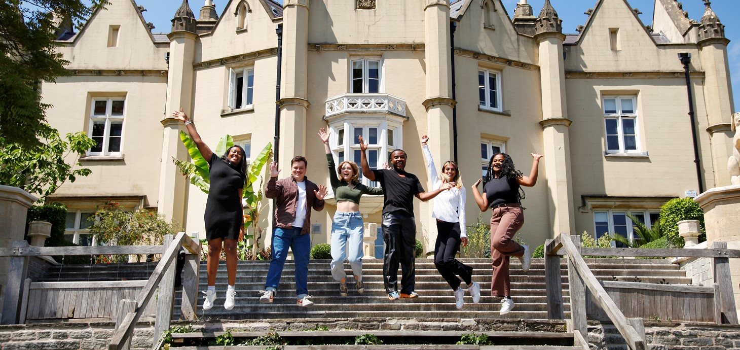 A group of students jump for joy outside Singleton Abbey 