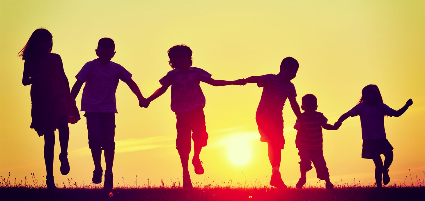 Silhouette of six people of various ages holding hands outside with sunset in background