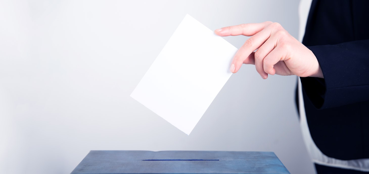 A photo of a person casting their vote using a ballot box.