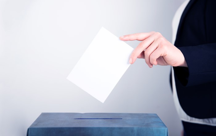 A photo of a person casting their vote using a ballot box.