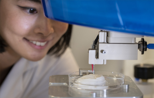 Woman using a 3d bioprinter to print cells