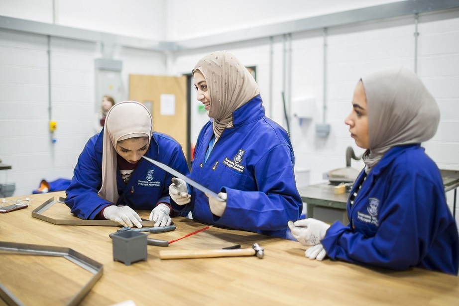 3 students working on a bench with materials 