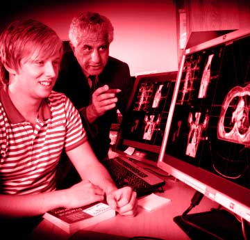 a male student being and male teacher looking at a computer screen