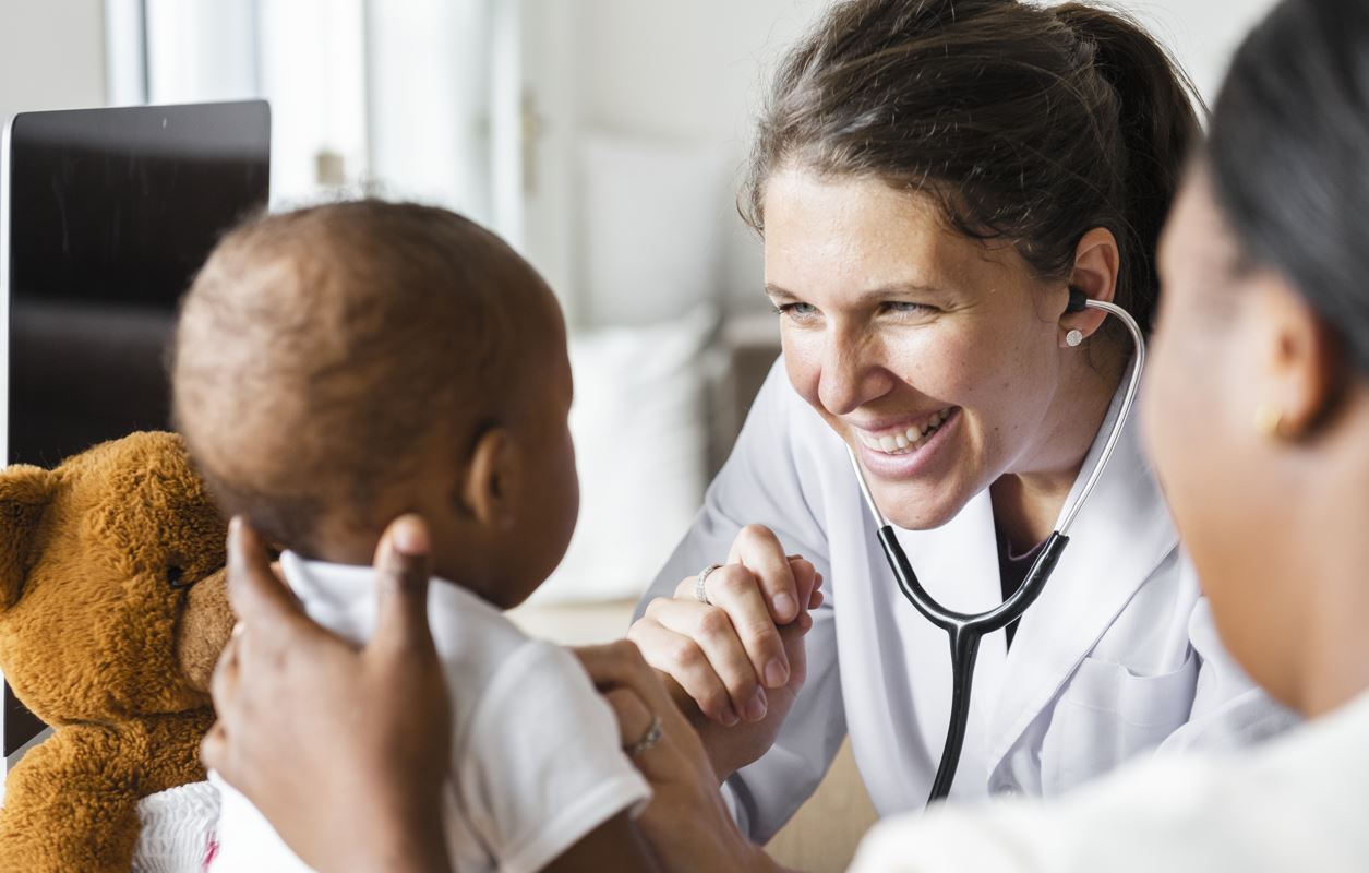 Doctor examining a toddler patient being held by mother