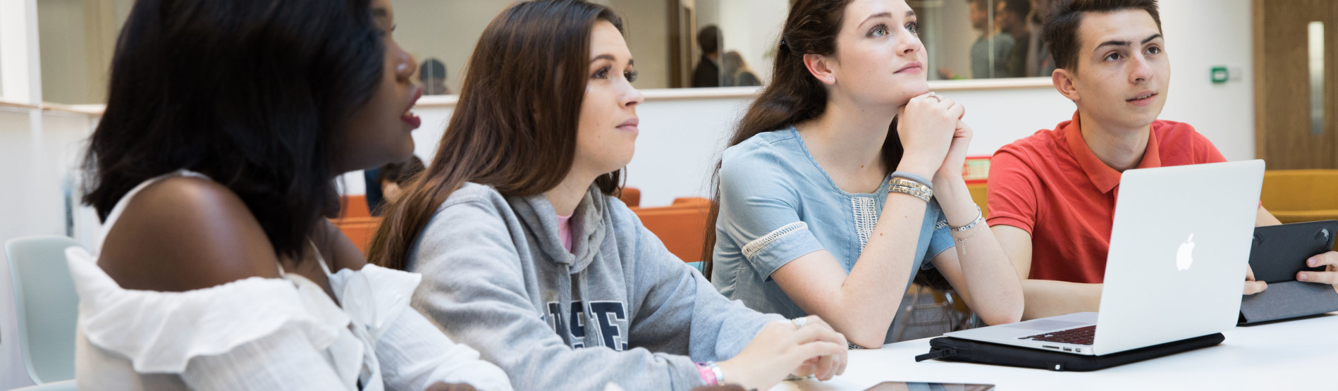 Four students sitting at a table listening attentively